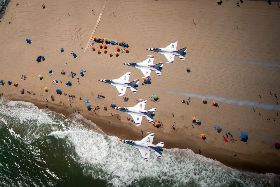 Jets fly in formation above a beach.