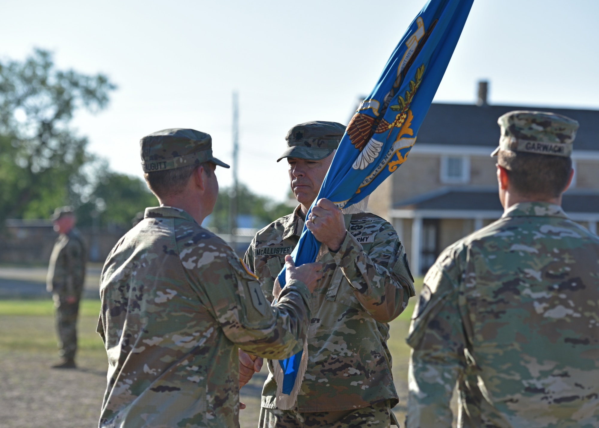 U.S. Army Lt. Col. John McAllister, middle, incoming 344th Military Intelligence Battalion commander, assumes command from Col. Loren Traugutt, 111th Military Intelligence Brigade commander, during the 344th MI BN change of command ceremony at Fort Concho, San Angelo, Texas, June 21, 2022. Through the passing of the guidon, Traugutt accepted command from Lt. Col. Joseph Garwacki, outgoing 344th MI BN commander, and transferred responsibility for accomplishing the mission to McAllister. (U.S. Air Force photo by Senior Airman Ashley Thrash)
