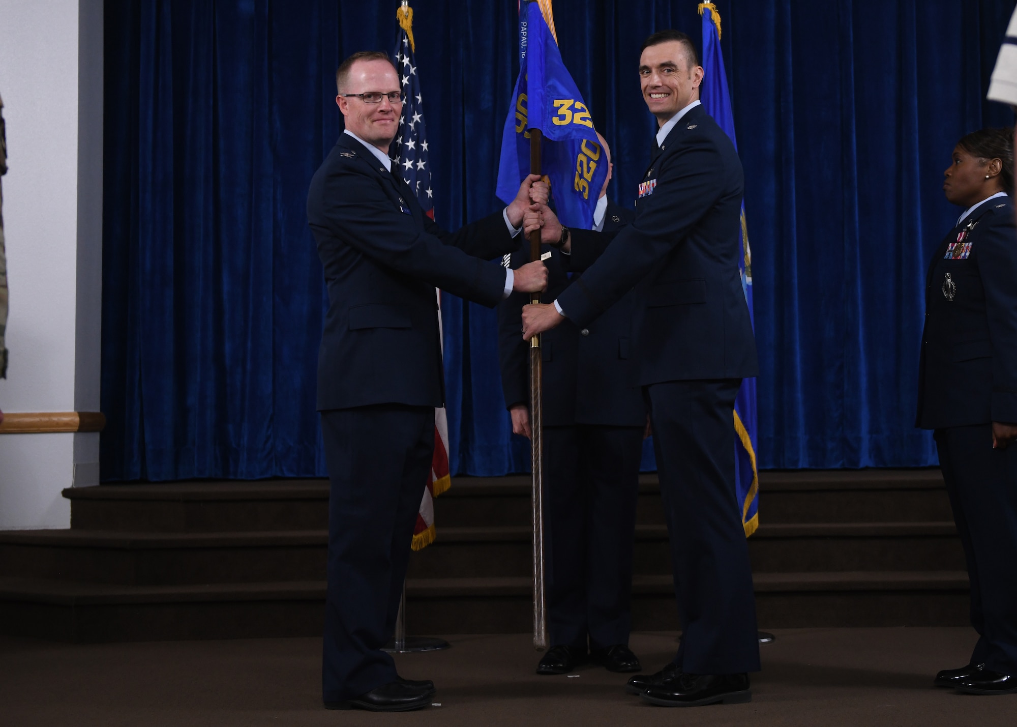 Col. Jared Nelson, commander of the 90th Operations Group, passes the guidon to Lt. Col. Aaron Linton, the incoming commander of the 320th Missile Squadron, during a change of command ceremony on F.E. Warren Air Force Base, Wyoming, June 21, 2022. The change of command ceremony signifies the transition of command from Lt. Col. Janet Dewese, the outgoing commander of 320 MS, to Linton. (U.S. Air Force photo by Airman 1st Class Darius Frazier.)