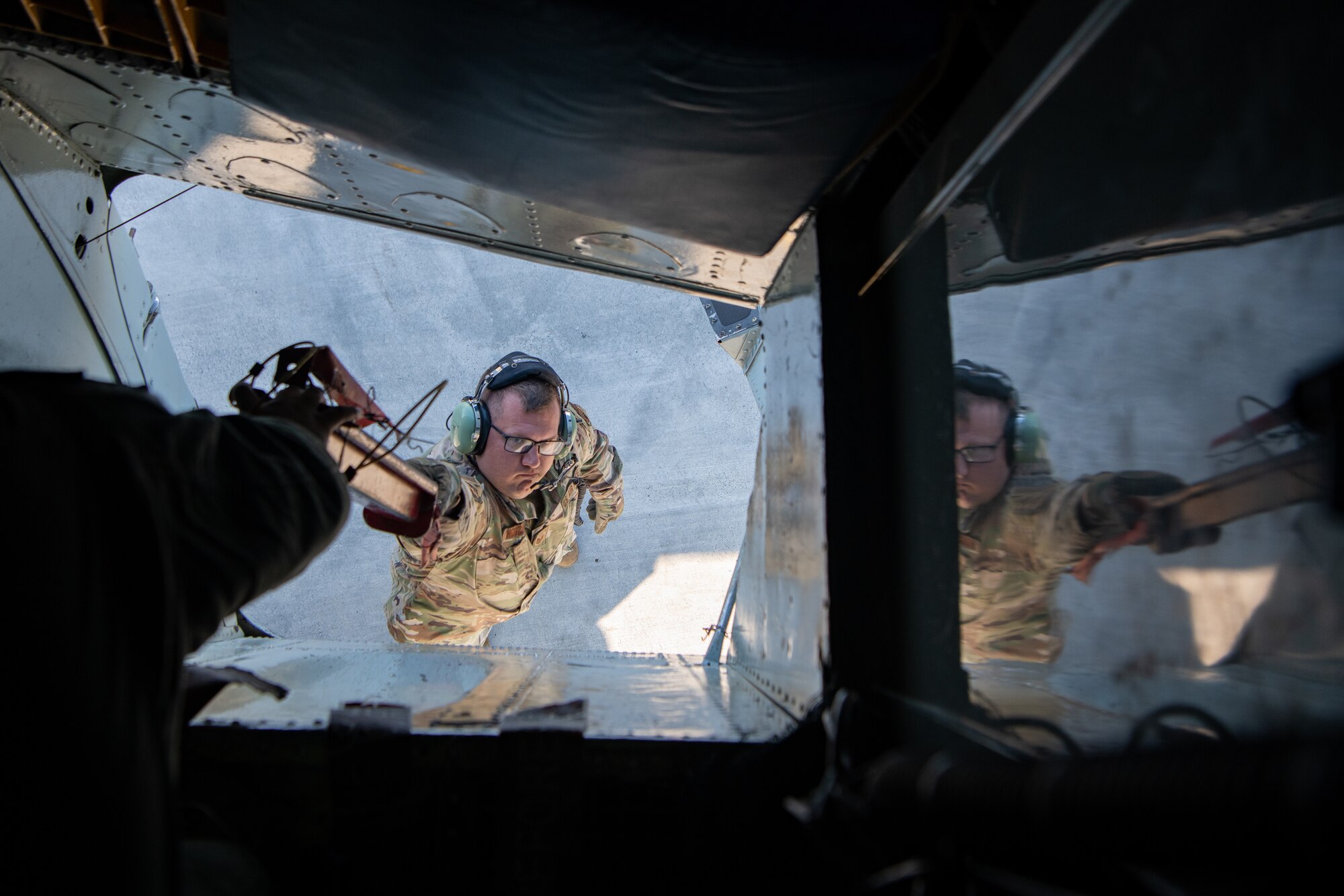 Equipment is handed out of the bottom hatch of a KC-135.