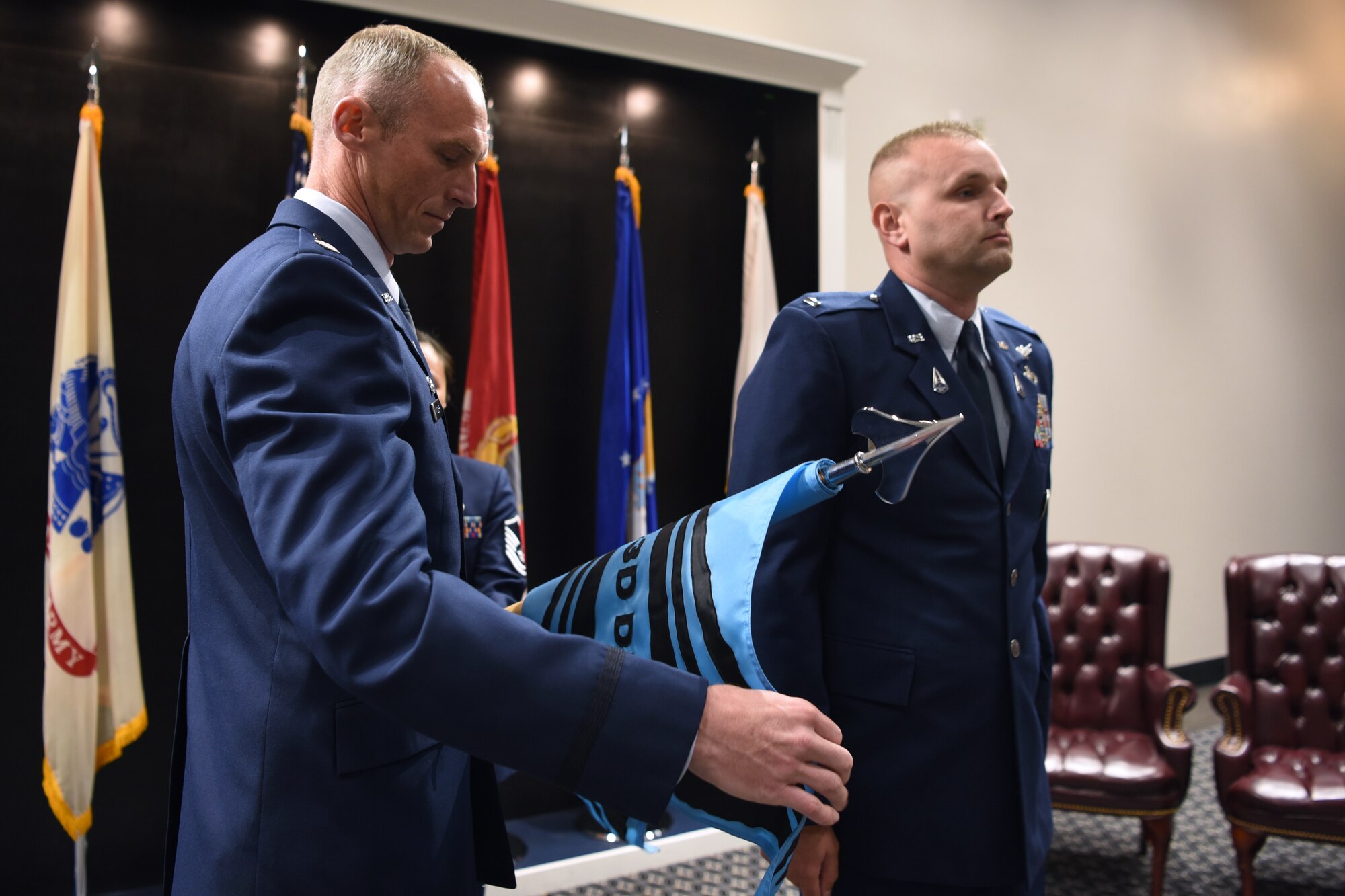 U.S. Space Force Lt. Col. Charles Cooper, 533rd Training Squadron commander, unrolls the Detachment 1 flag during the activation and assumption of responsibility for 533rd TRS, Det 1, at the Powell Event Center, Goodfellow Air Force Base, Texas, June 21, 2022. The Det 1 guidon identified the unit and its affiliation. (U.S. Air Force photo by Senior Airman Abbey Rieves)