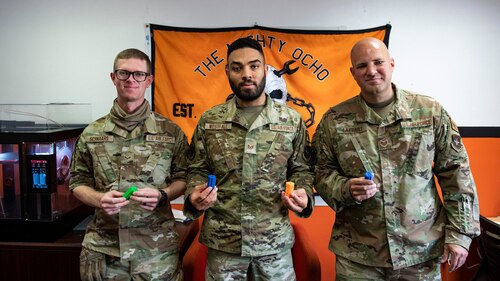 (left to right) Senior Airman Daniel Schnaars, Staff Sgts. Trenton Westfall and Kirk Laytart, all from the 87th Aerial Port Squadron, pose on April 11, 2022 with four different prototypes of the shower faucet handles they designed and 3D-printed for a dormitory building on Al Udeid Air Base, Qatar. Of the eight showers in the dorms, six of the showers had broken handles, negatively impacting more than 100 Airmen on the base. Schnaars, Westfall and Laytart spent about 35 man-hours developing, testing and installing prototypes to replace the faucet handles, bringing the showers back to 100 percent operability