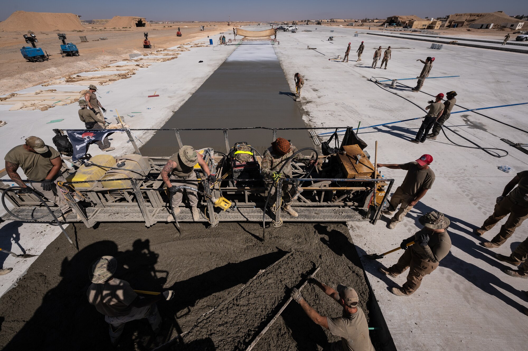 1st Expeditionary Civil Engineer Squadron Pavements and Heavy Equipment Operators place, finish, and burlap a new lane during a runway overrun repair project at an undisclosed location in Southwest Asia, June 8, 2022. The 1st ECES is placing a total of 12,000 cubic meters throughout the entire project. This single pour is 340 cubic meters. (U.S. Air Force photo by Master Sgt. Christopher Parr)