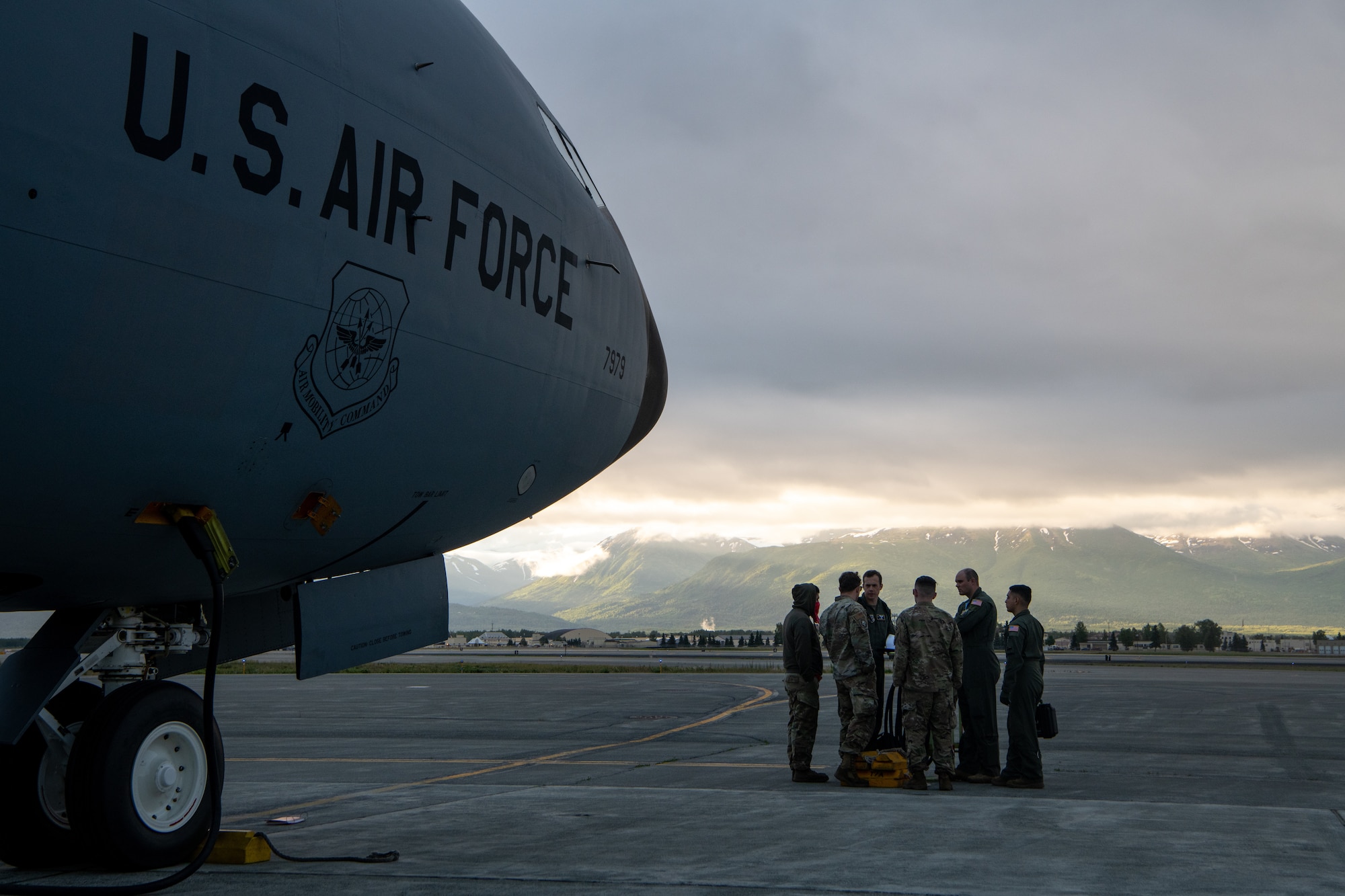 Airman stand at the front of a plane before a flight.