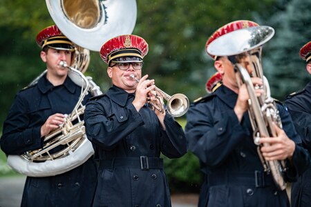 Three soldiers play brass instruments.