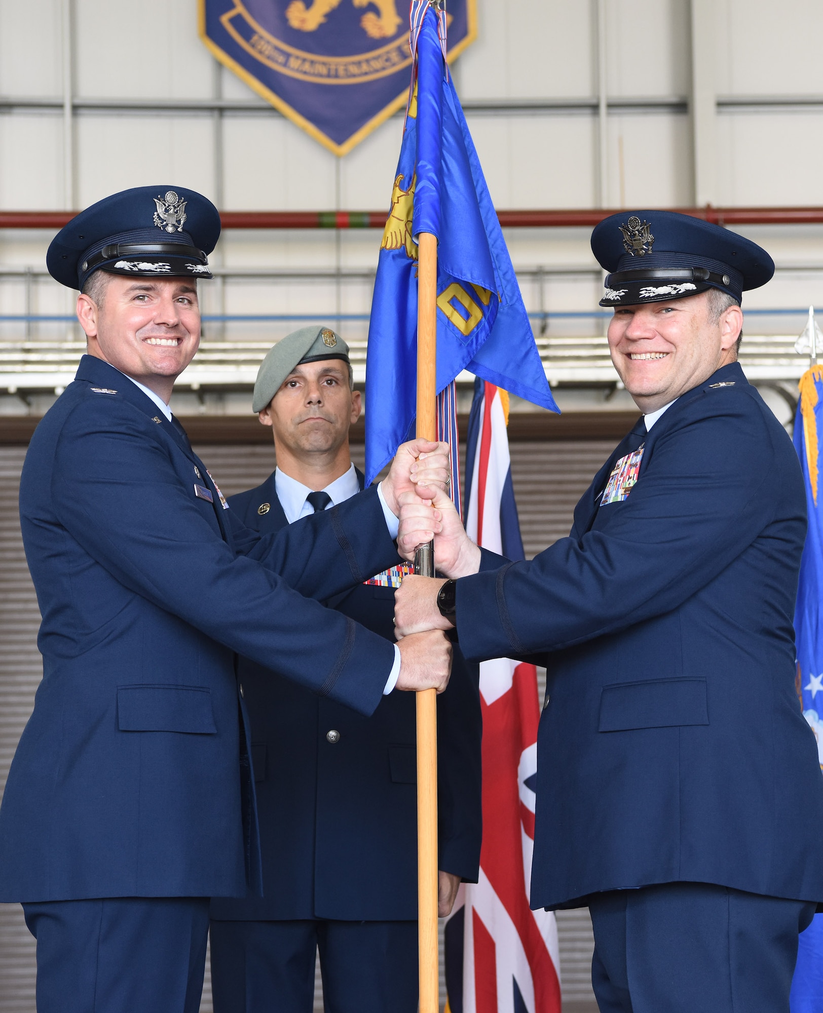 U.S. Air Force Col. Gene Jacobus, left, 100th Air Refueling Wing commander, passes the guidon to Col. Thomas Hutton, new 100th Operations Group commander, during a change of command ceremony at Royal Air Force Mildenhall, England, June 16, 2022. Passing the guidon is a formal process during a change of command ceremony and signifies the transfer of leadership from one officer to another. (U.S. Air Force photo by Karen Abeyasekere)