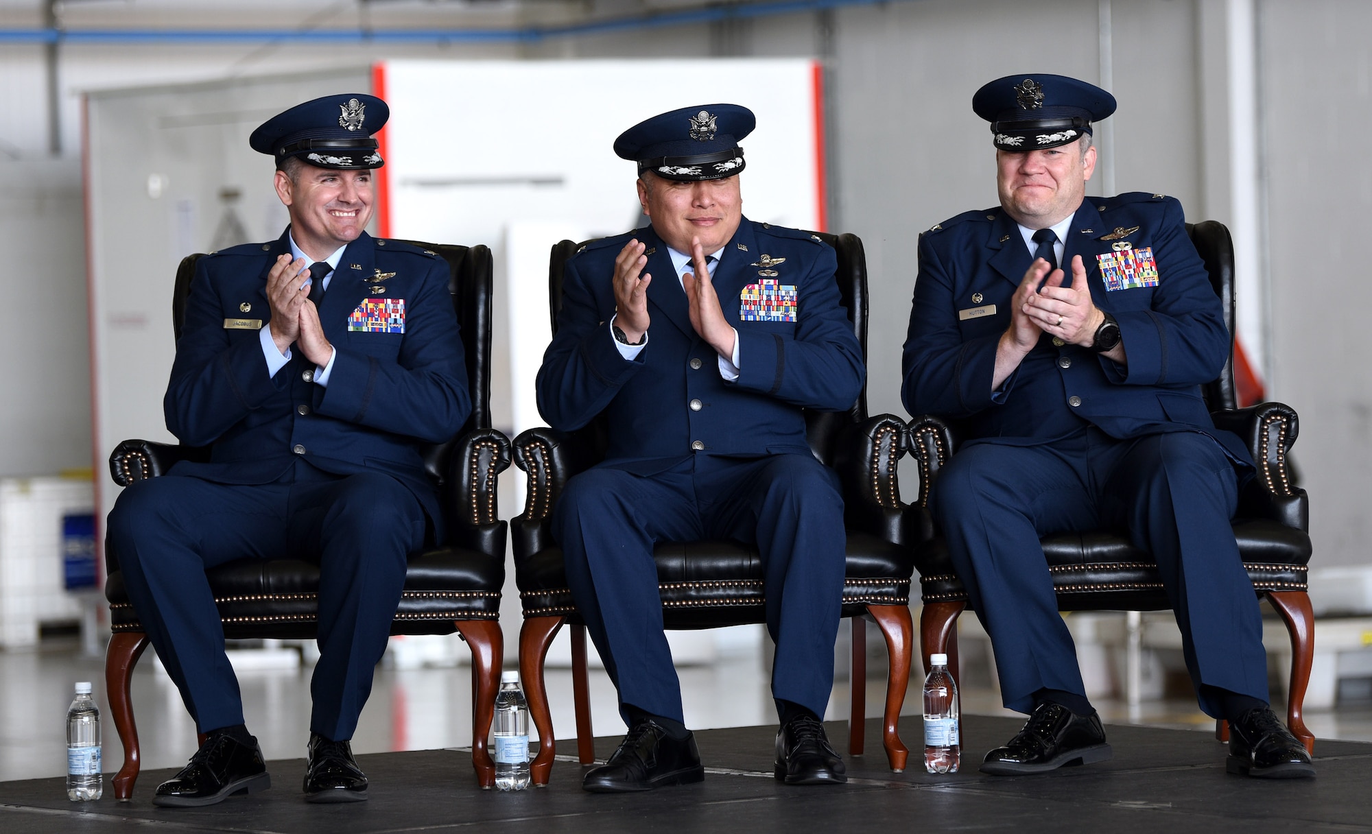 U.S. Air Force Col. Gene Jacobus, left, 100th Air Refueling Wing commander; Col. Van Thai, center, 100th Operations Group commander, and Col. Thomas Hutton, new 100th OG commander, applaud as guests are welcomed during their change of command at Royal Air Force Mildenhall, England, June 16, 2022. Hutton joins the 100th ARW from Ramstein Air Base, Germany, and Thai is now at Yakota Air Base, Japan. (U.S. Air Force photo by Karen Abeyasekere)