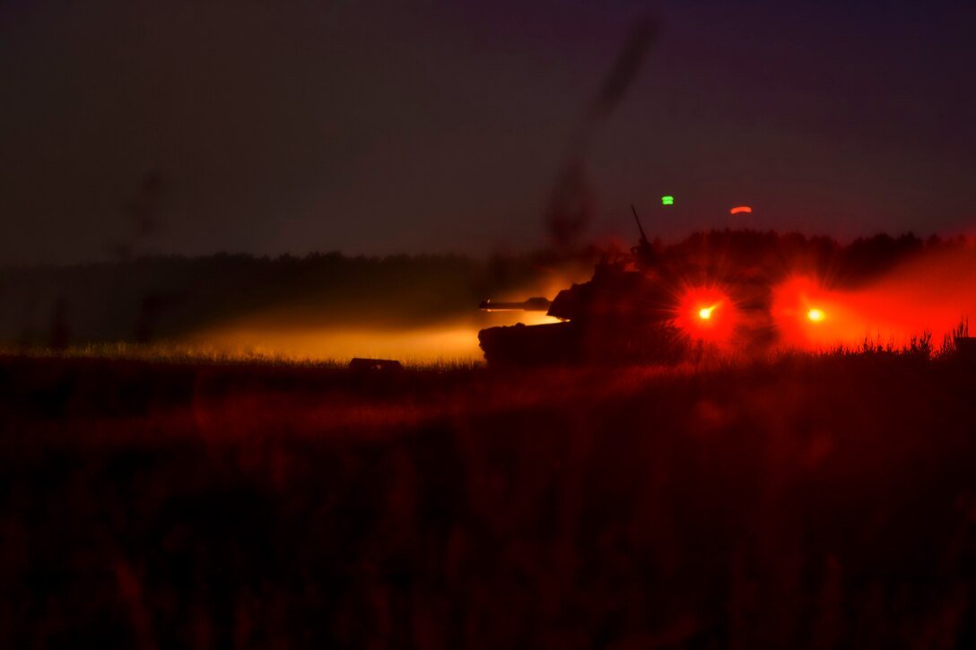 A tank with red lights is seen at night.