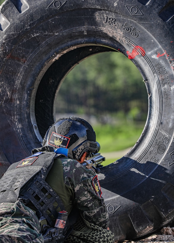 A Honduran sniper fires through a tire during the combined sniper assault course for the Fuerzas Comando 2022 competition.