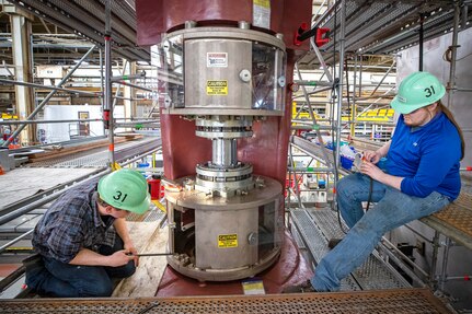 AJ Banks, left, machinist mechanic, and Kyle Farrell, machinist helper, Shop 31, Machinists, Electroplaters & Toolmakers, use a boring bar to taper the port rudder from the USS Theodore Roosevelt (CVN 71) May 13, 2022, at Puget Sound Naval Shipyard & Intermediate Maintenance Facility in Bremerton, Washington. (U.S. Navy photo by Scott Hansen)