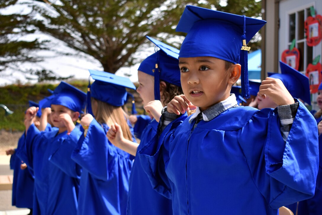 Children dance in blue caps and gowns.