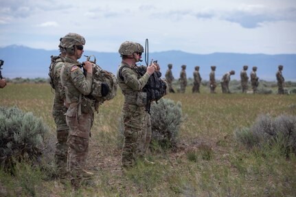 Forward observers stand outside the landing  zone as two UH-60 helicopters land to take these soldiers out to an observation point to train on marking targets for artillery during Western Strike 22, June 9, 2022