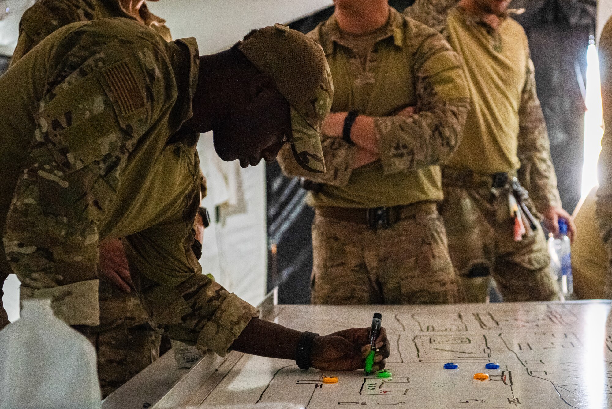 An Airman plans movements for an operations using a marker on a dry erase board.