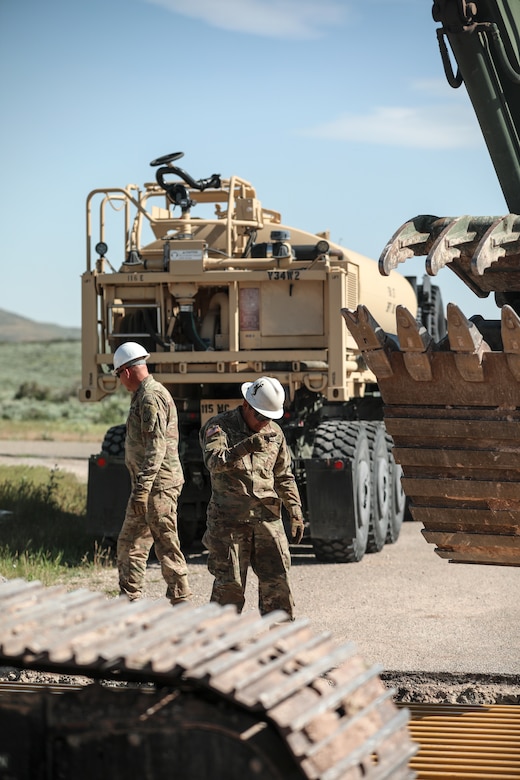 A Soldier in 3rd Platoon, 116th Engineer Company, 1457th Engineer Battalion, Utah National Guard guides an excavator operator while installing a new cattle guard at Dinosaur National Monument, June 13, 2022