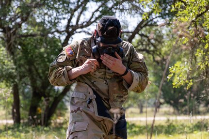 Spc. Sean Doyle, a squad member representing the U.S. Army South's best squad competition team puts on his M50 gas mask during the medical lane during the Army Futures Command 2022 Best Squad Competition on June 7, 2022 at Camp Bullis, Texas. The Best Squad Competition is being used to select the team that will represent their command at the next level of competition with the hope of eventually winning the inaugural U.S. Army level Best Squad Competition