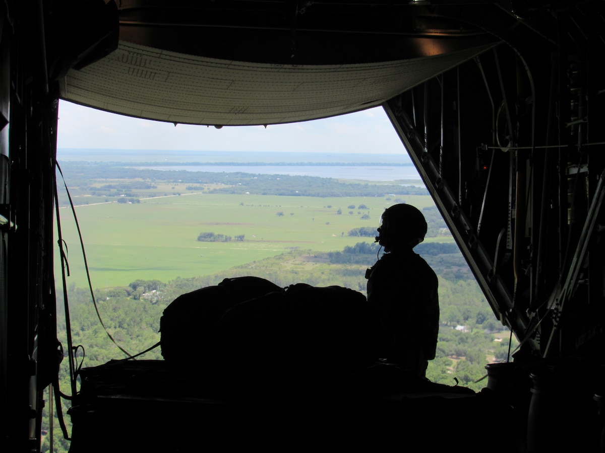 A loadmaster prepares to drop a container delivery system from open back from of a C-130H Hercules.
