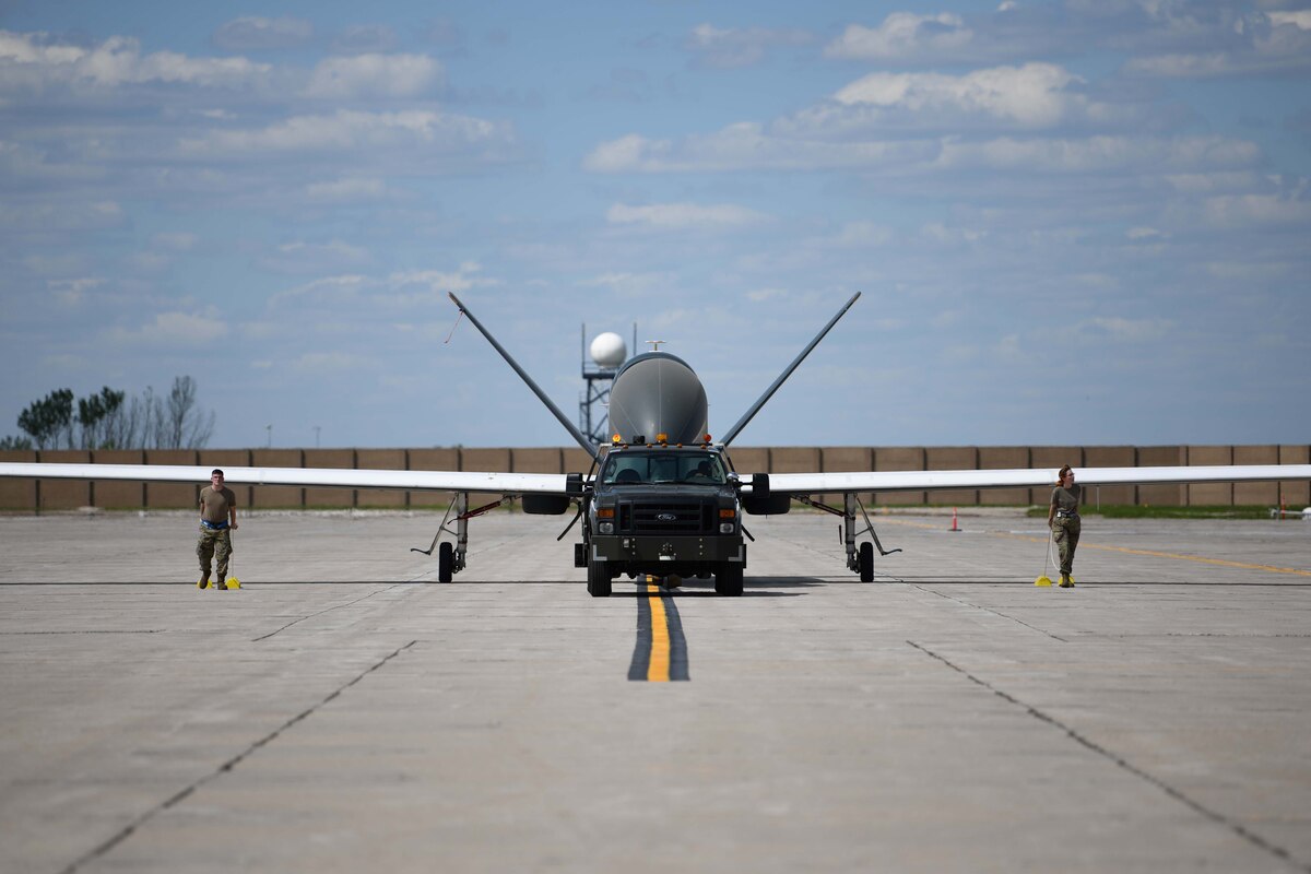 Airmen assigned to the 319th Aircraft Maintenance Squadron from Grand Forks Air Force Base, North Dakota, tow an RQ-4 Block 30 Global Hawk remotely piloted aircraft June 6, 2022, across the Grand Forks Air Force Base flight line to Northrop Grumman at Grand Sky. This was the first of five RQ-4 Block 30s to be transferred to Grand Sky to be outfitted with different sensor technology and begin operating as a part of the Test Resource Management Center’s High Speed System Test department. Located on Grand Forks Air Force Base, Grand Sky is a business and aviation park focused on developing and growing the unmanned aerial systems industry. (U.S. Air Force photo by Senior Airman Ashley Richards)