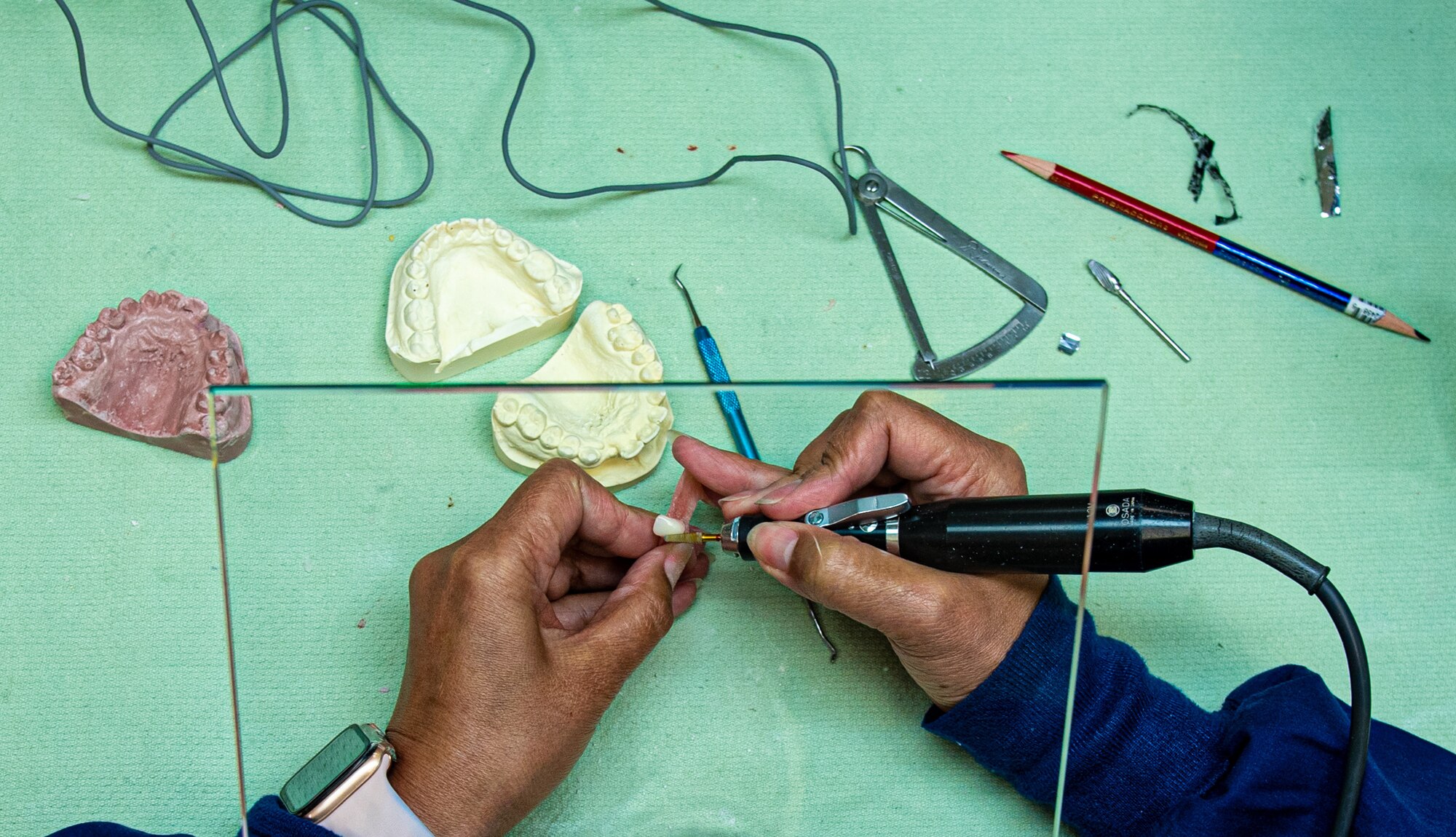 A woman drills a denture.