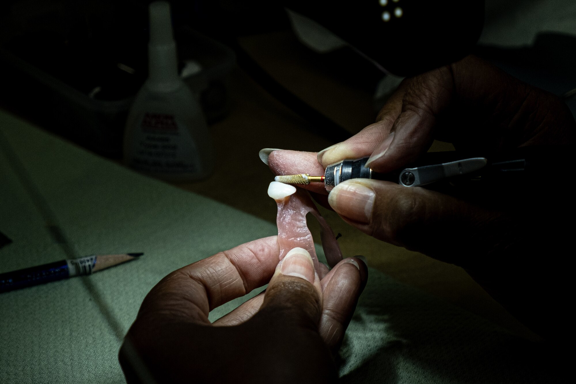 A woman drills a crown for a tooth.