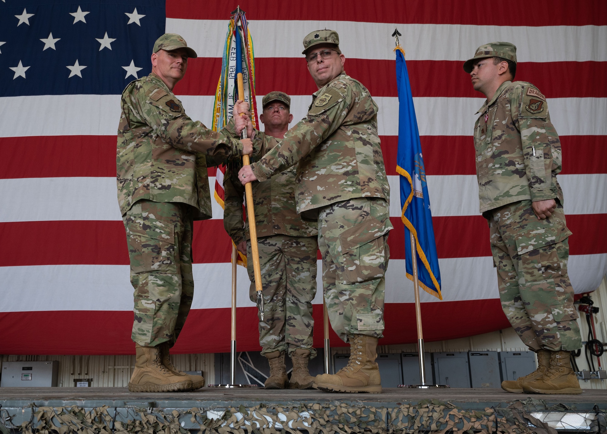 Military members conduct a ceremony with a guidon flag.