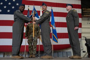 Military members conduct a ceremony with a guidon flag.