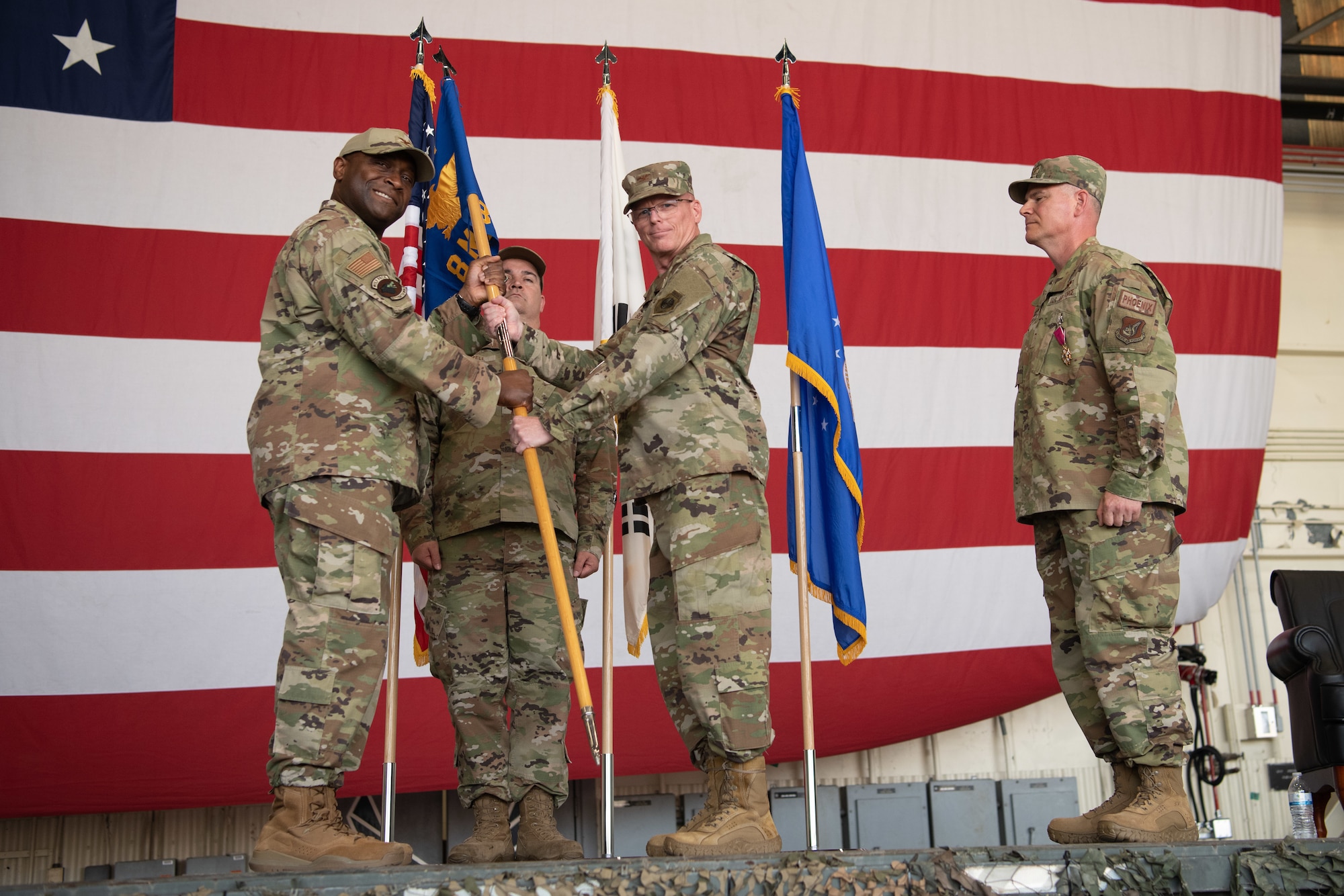 Military members conduct a ceremony with a guidon flag.