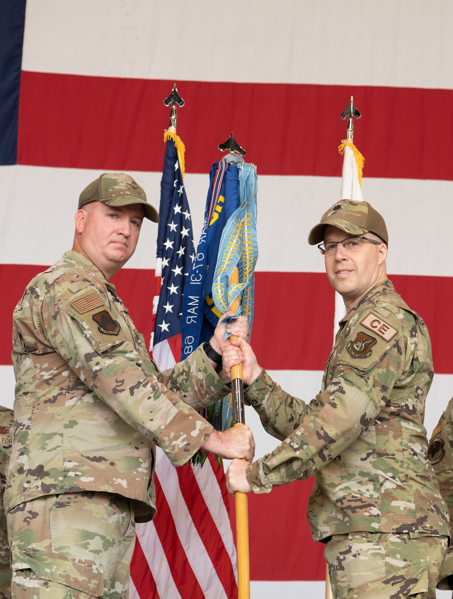 Military members conduct a ceremony with a guidon flag.