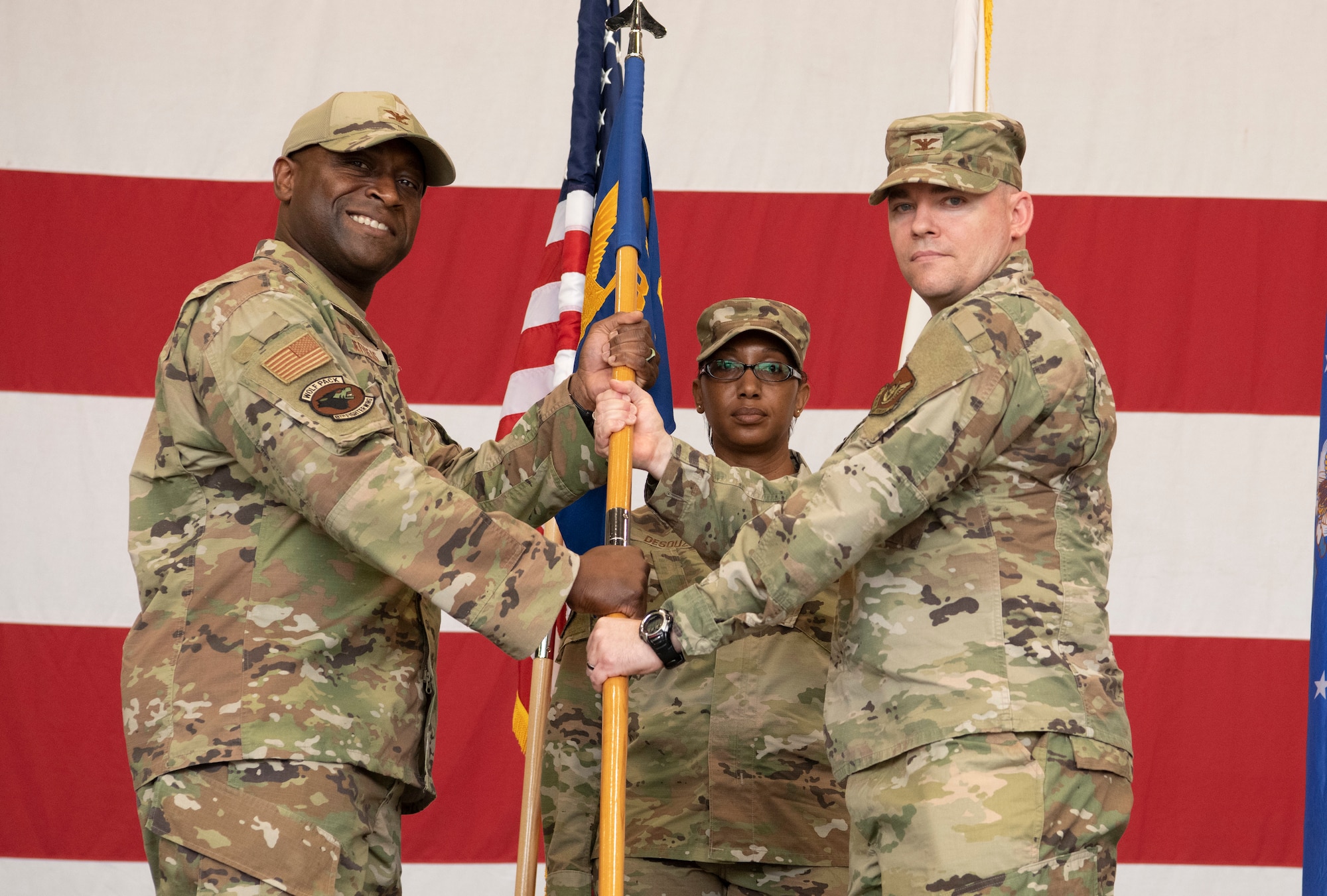 Military members conduct a ceremony with a guidon flag.