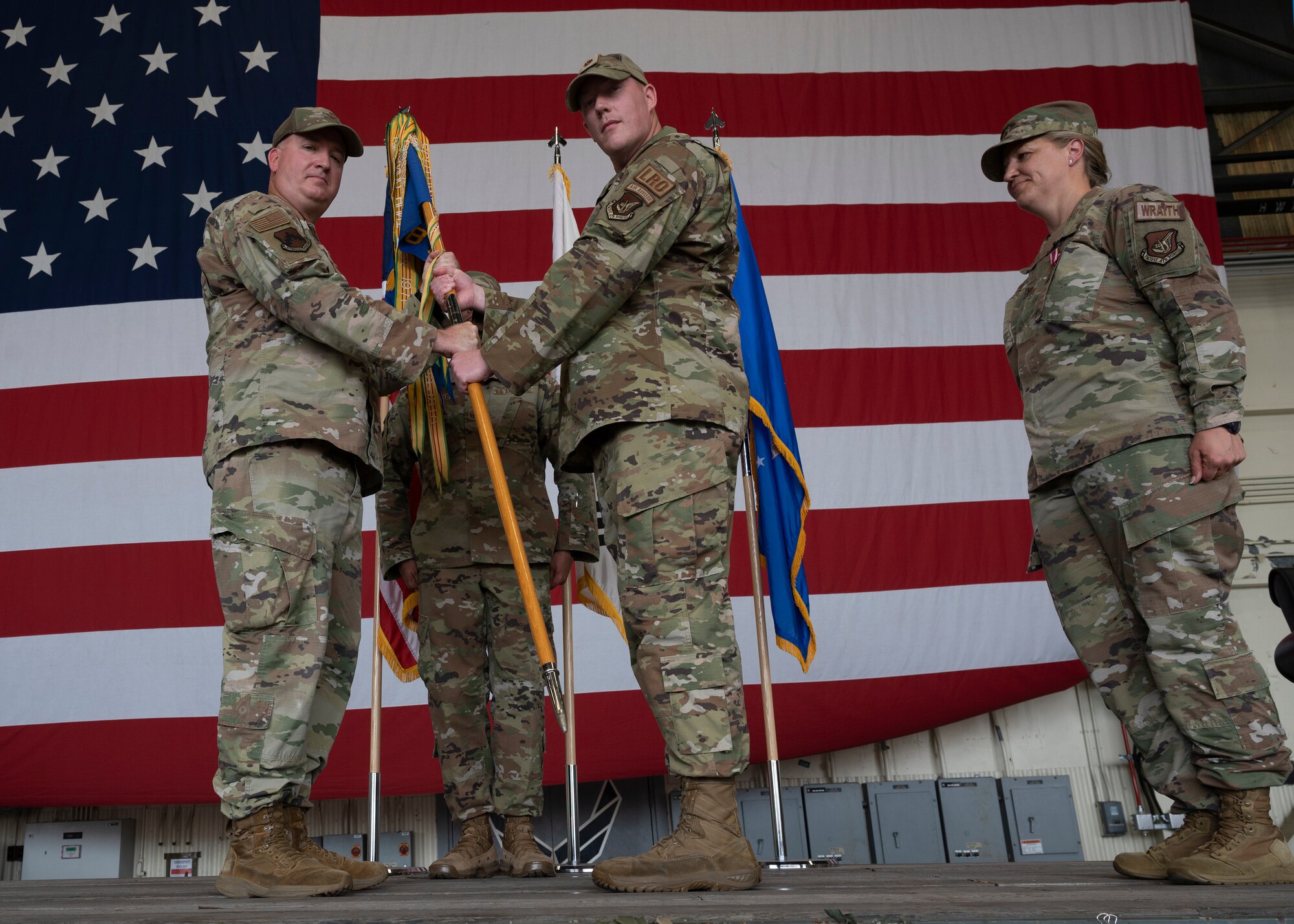 Military members conduct a ceremony with a guidon flag.