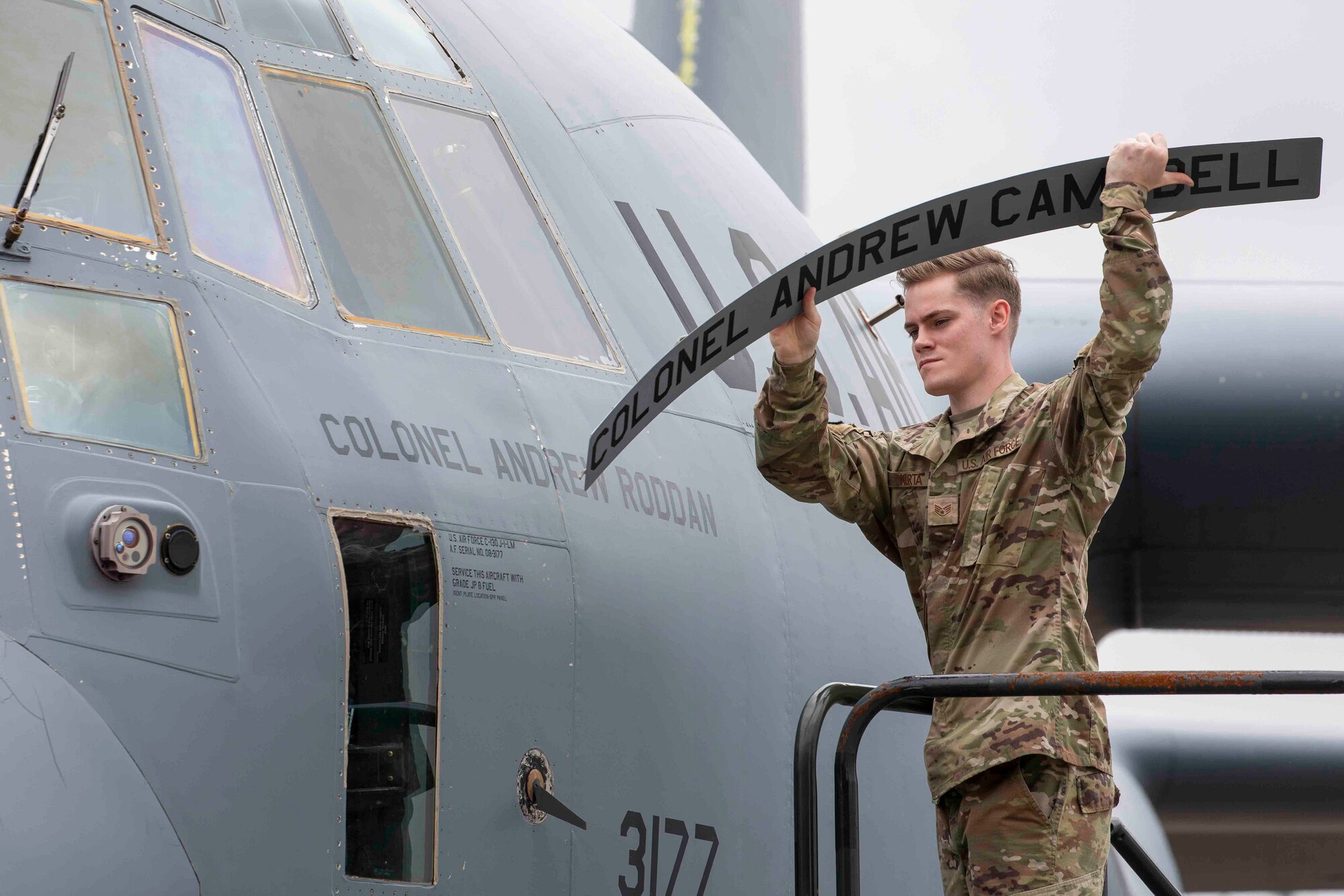 A U.S. Air Force Airman unveils a nametape on a C-130J Super Hercules