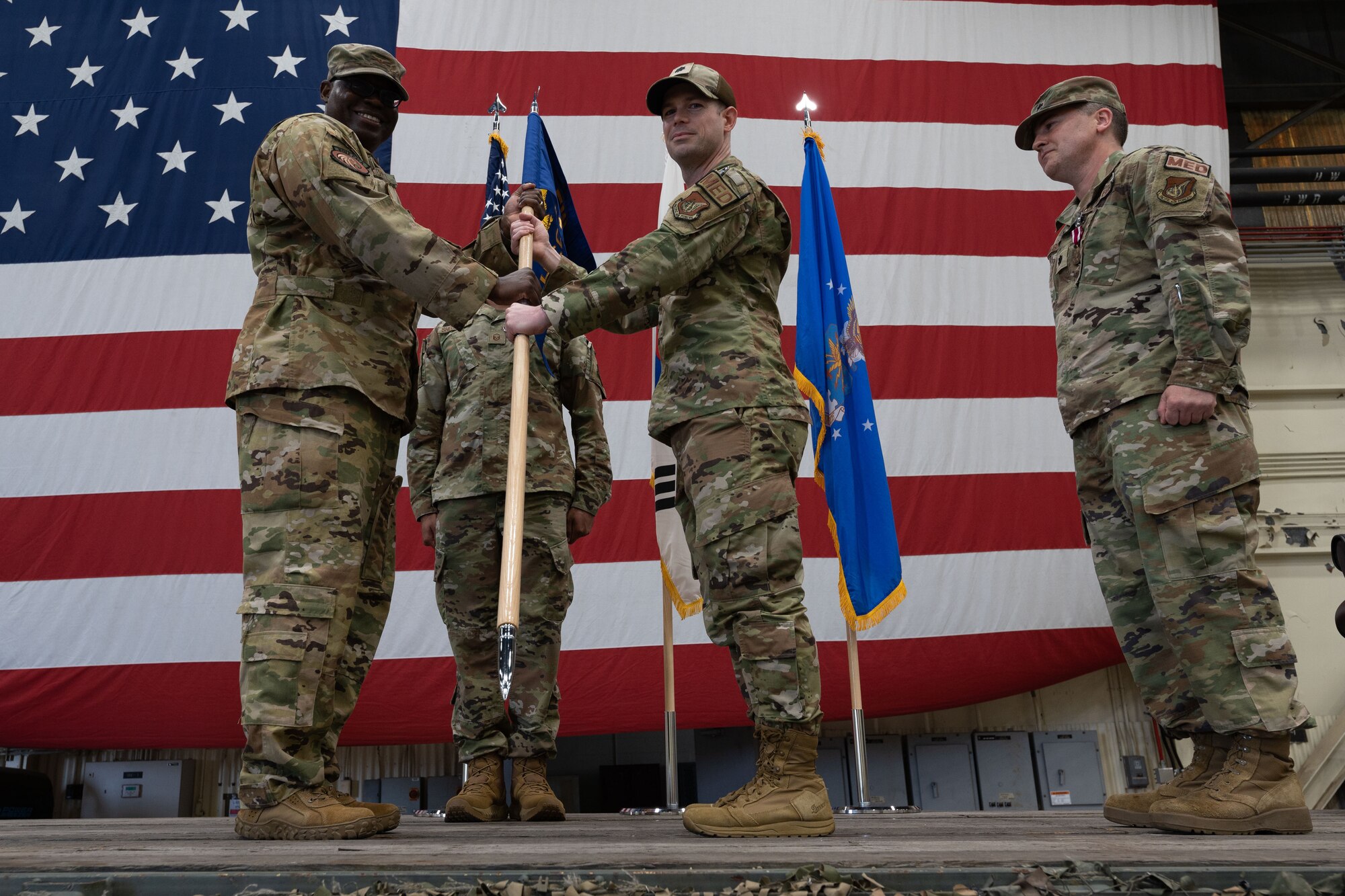 Military members conduct a ceremony with a guidon flag.