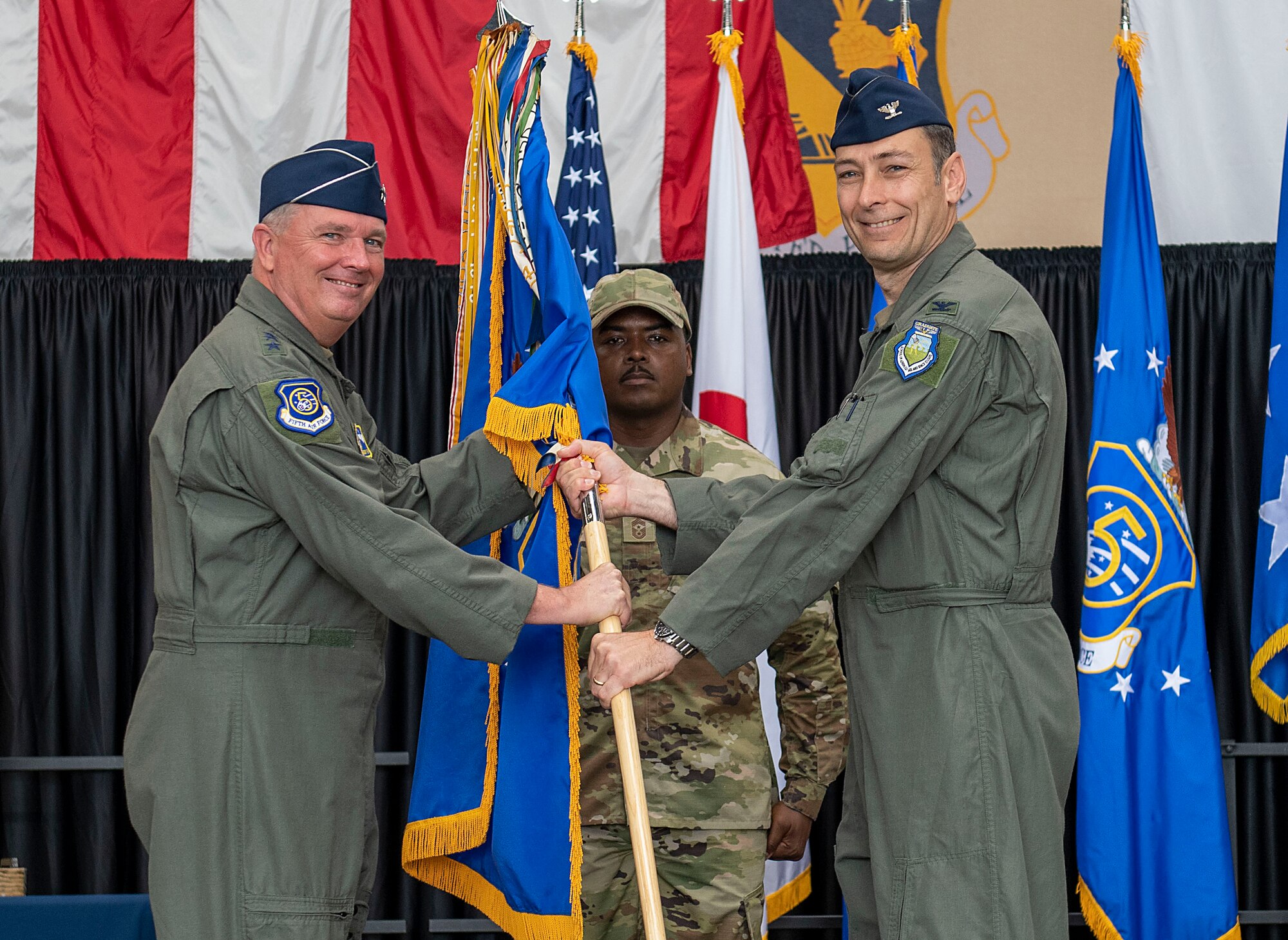 Col. Andrew L. Roddan, 374th Airlift Wing incoming commander, right, receives a guidon from Lt. Gen. Ricky Rupp