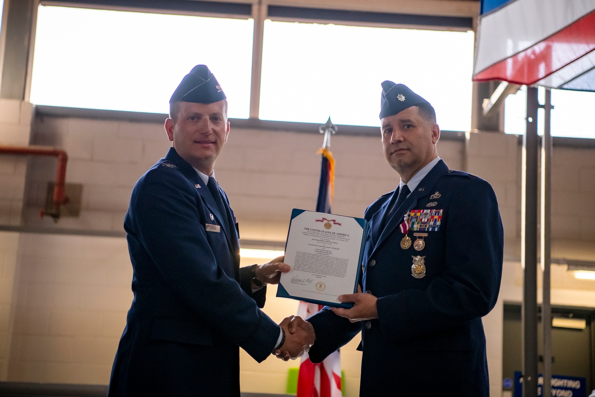 U.S. Air Force Col. Richard Martin, left, 423d Air Base Group commander, presents the Meritorious Service Medal citation to Lt. Col. Hans Winkler, 423d Civil Engineer Squadron commander, during a change of command ceremony at RAF Alconbury, England, June 22, 2022. During his command, Winkler led a multinational workforce of 196 military and civilian personnel in the sustainment, maintenance, repair, fire protection and emergency services for 697 facilities across a two-installation and 916 acre complex. (U.S. Air Force photo by Staff Sgt. Eugene Oliver)