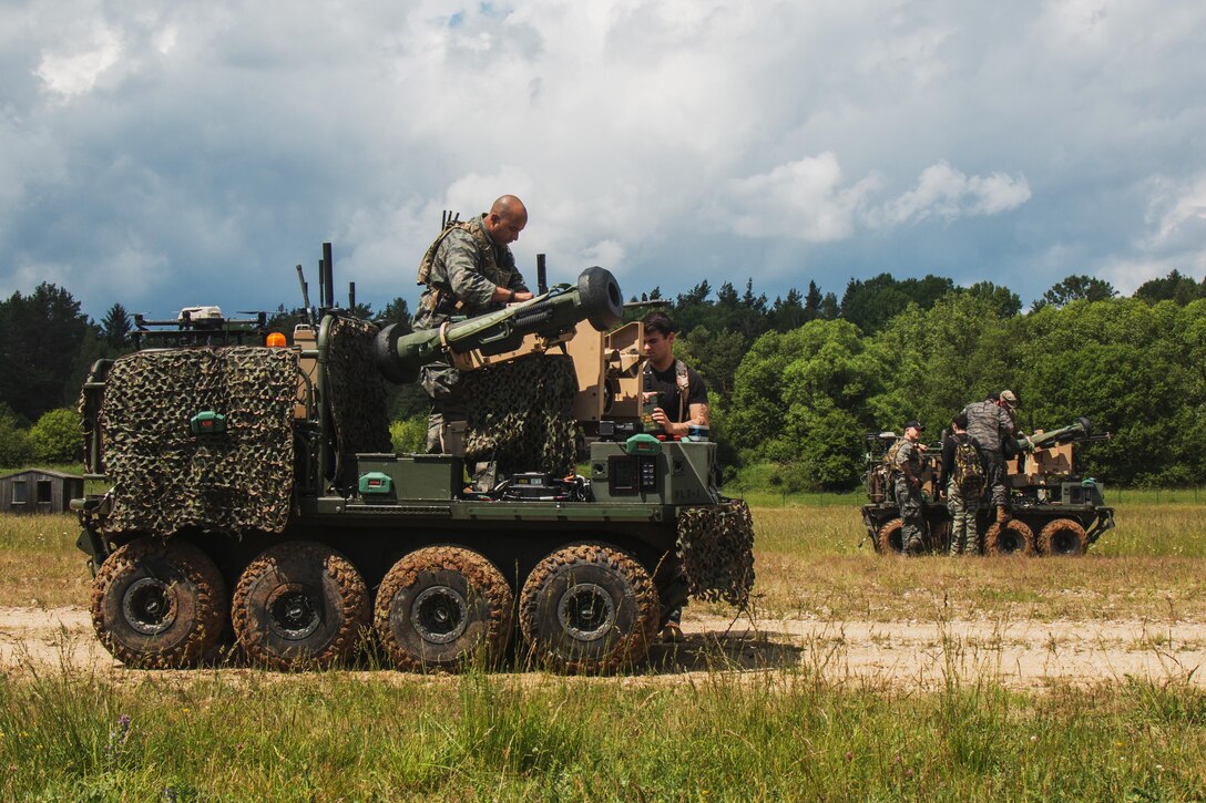 Soldiers examine two wheeled vehicles in a field.