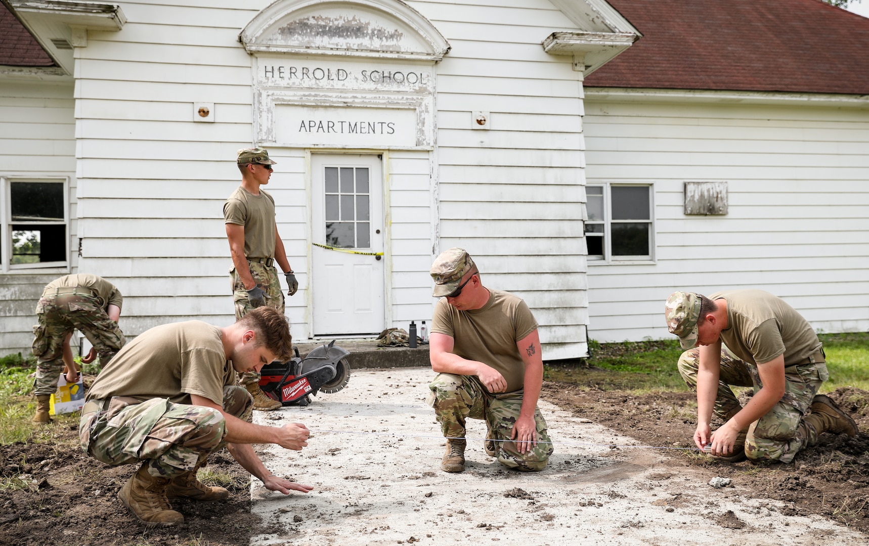 Iowa Army National Guard Soldiers assigned to the 831st Engineer Company mark a straight line with thread on newly poured concrete at the historic Herrold School House in the Camp Dodge training area in Johnston, Iowa, June 14, 2022. The 831st EC was assigned to complete various projects around Camp Dodge.