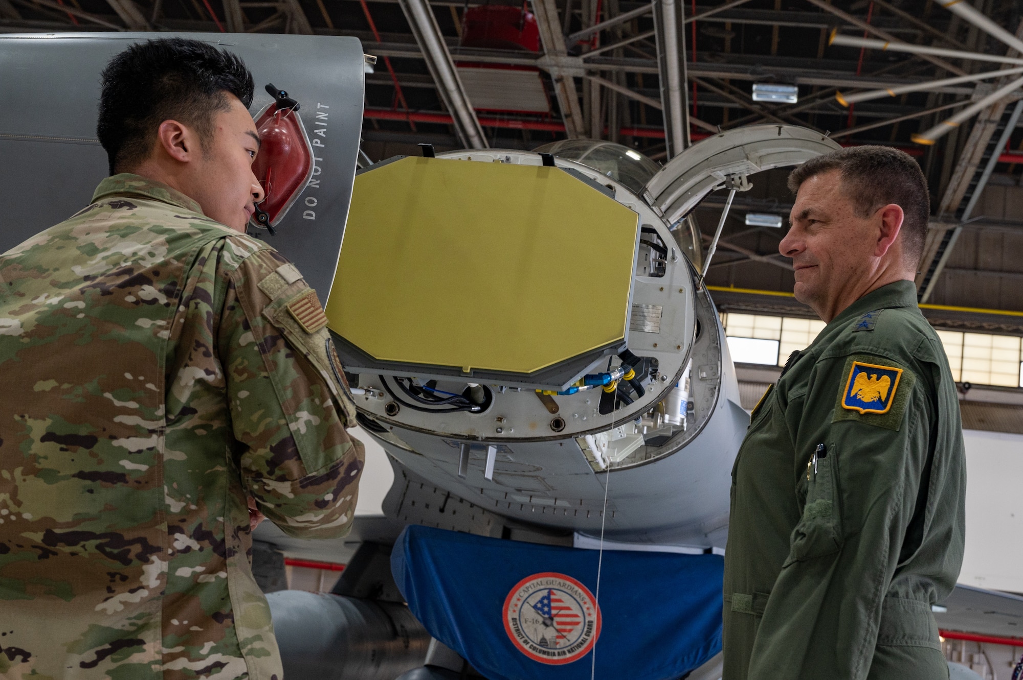 U.S. Air Force Staff Sgt. Jackie Zheng, left, avionics specialist, 113th Wing, District of Columbia National Guard (DCNG), briefs Lt. Gen. Michael A. Loh, right, director, Air National Guard, on the specifications of the APG-83 Active Electronically Scanned Array (AESA) radar now equipped on F-16 Fighting Falcon aircraft assigned to the DCNG on Joint Base Andrews, Maryland, June 9, 2022.