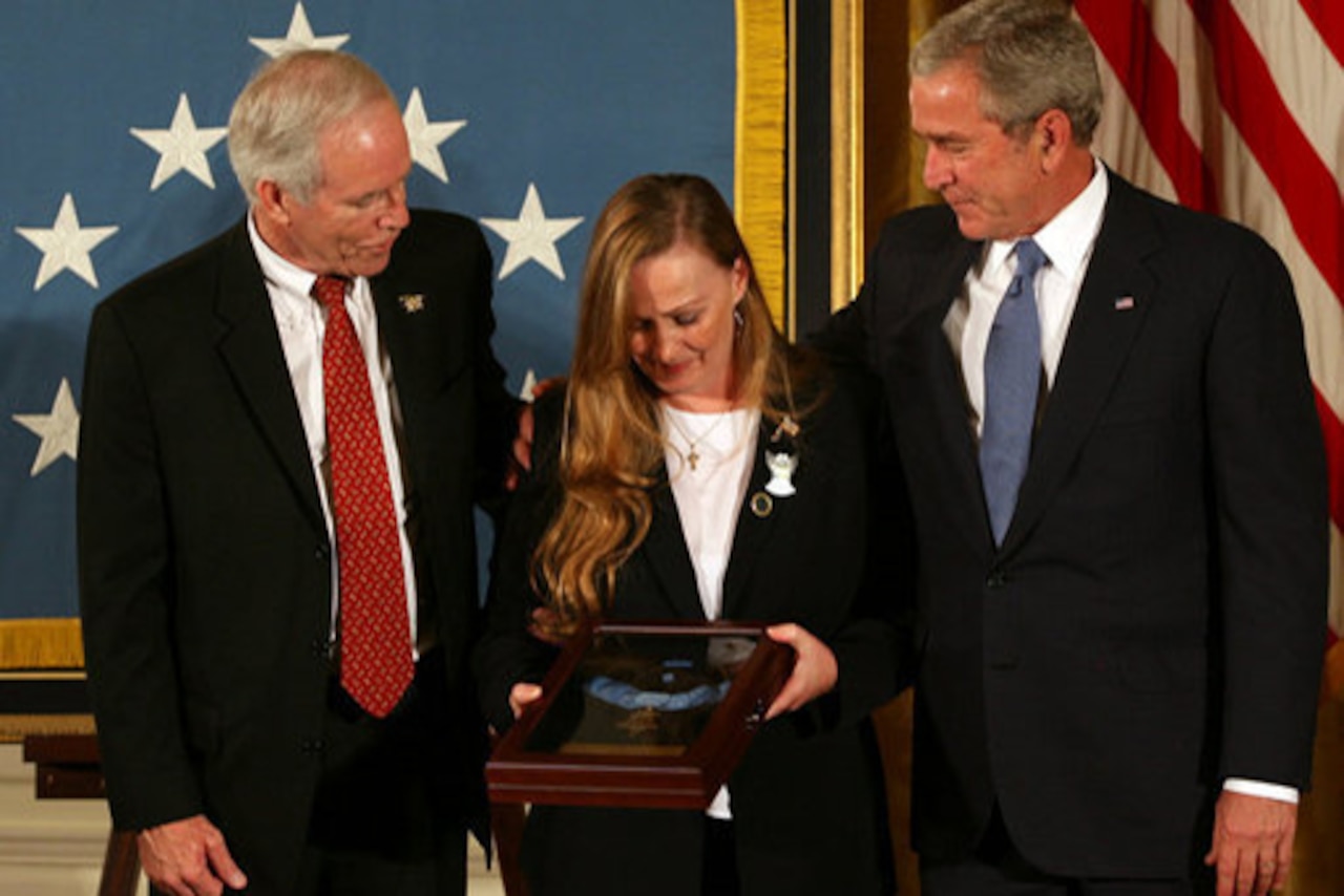 A woman holds a plaque that two men beside her look at.