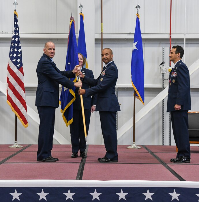 Air Force Test Center Commander Maj. Gen. Evan Dertien, left, hands the Arnold Engineering Development Complex guidon to Col. Randel Gordon charging him with command of AEDC during the Change of Command Ceremony June 16, 2022, in the Aircraft Test Support Facility at Arnold Air Force Base, Tennessee. Also pictured are Col. Jeffrey Geraghty, right, previous AEDC commander, and Chief Master Sgt. Jennifer Cirricione, senior enlisted leader, AEDC. (U.S. Air Force photo by Jill Pickett)