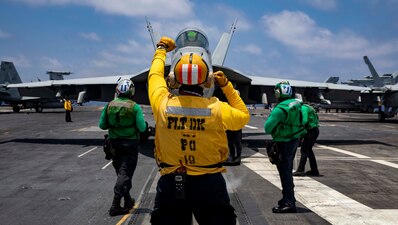 Aviation Boatswain's Mate (Handling) 1st Class Jose Mercado signals to an F/A-18E Super Hornet aircraft attached to Strike Fighter Squadron (VFA) 86 during flight operations aboard the Nimitz-class aircraft carrier USS George H. W. Bush (CVN 77), June 16, 2022.