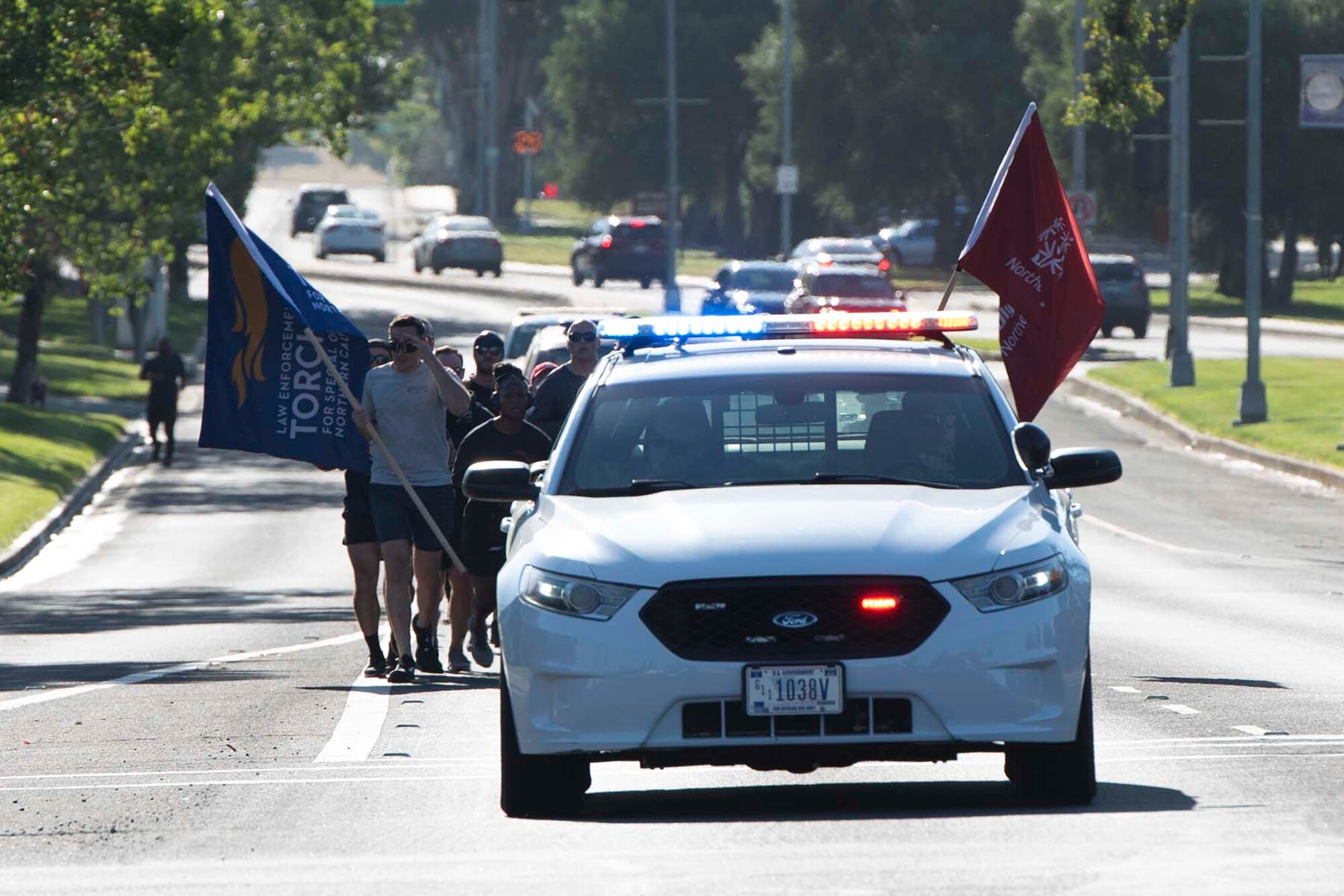 Airmen run on base behind a law enforcement car