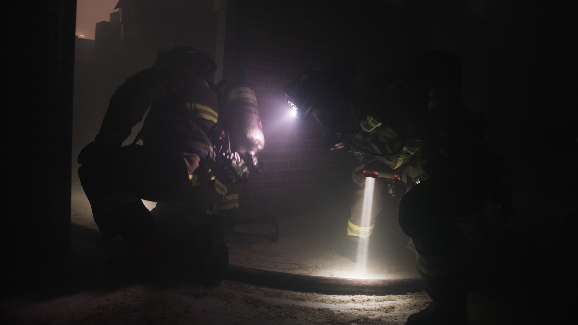 Firefighters search a building.
