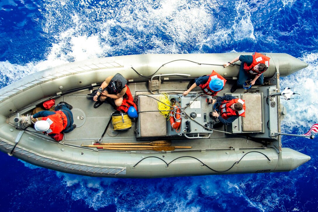 Sailors transit a body of water in small inflatable boat.