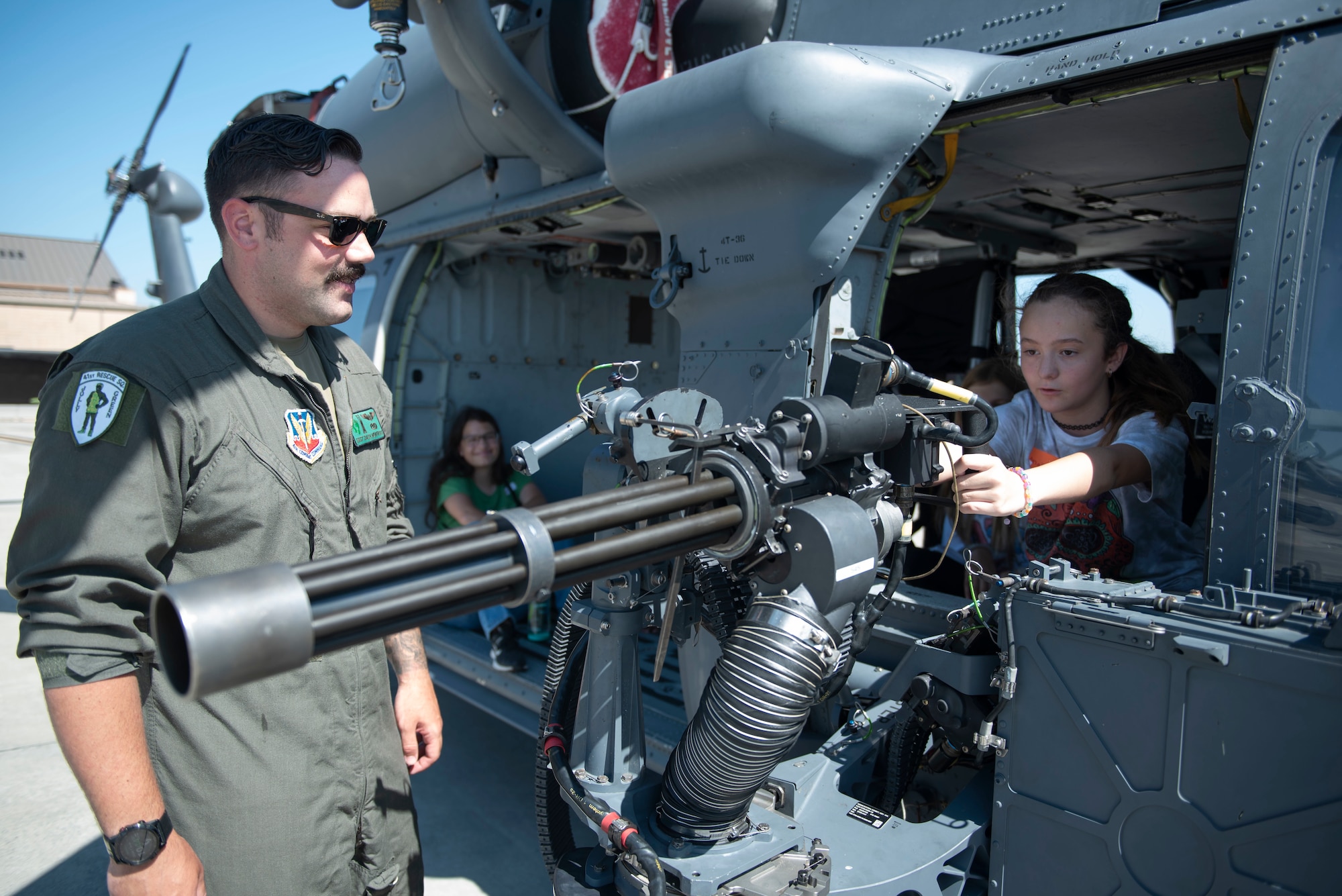 U.S. Air Force Staff Sgt. Zach Newfrock, 41stRescue Squadron special missions aviator, shows a teen the armaments of a HH-60W Jolly Green II during Teen Shadow Day at Moody Air Force Base, Georgia, June 22, 2022. Teen Shadow Day gave Moody Youth Center teens a chance to explore various careers in the U.S. Air Force. (U.S. Air Force photo by Staff Sgt. Thomas Johns)