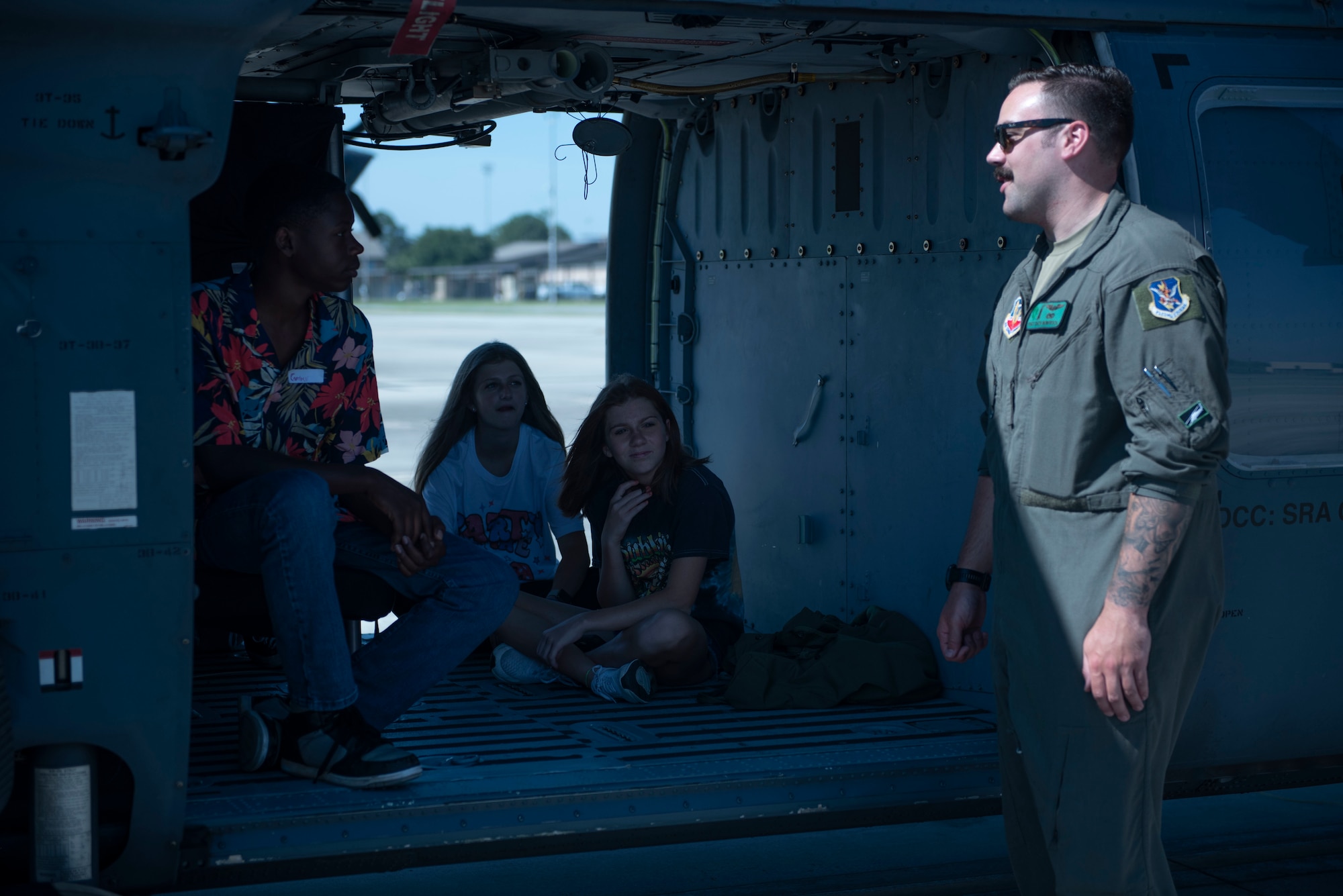 U.S. Air Force Staff Sgt. Zach Newfrock, 41st Rescue Squadron special missions aviator, educates teens from the Moody Youth center about the HH-60W Jolly Green II helicopter during Teen Shadow Day at Moody Air Force Base, Georgia, June 22, 2022. This photo was captured by Nicolas J., public affairs Teen Shadow Day participant. (Courtesy photo by Teen Shadow Day participant Nicolas J.)