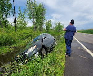 After being helped from the pictured vehicle by OSI Special Agent Damian Lonergan on June 15, 2022, the driver assesses the situation after veering off Minoa Road into the Cicero Swamp Wildlife Management Area eastbound towards Bridgeport, N.Y. (Photo by SA Damian Lonergan, OSI PF Det. 6, OL-C)