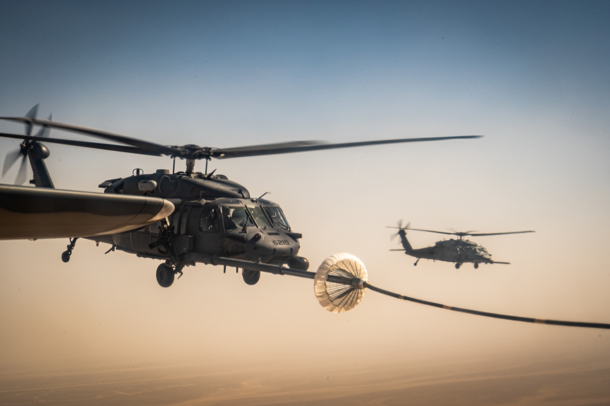 A 332d Air Expeditionary Wing HH-60G Pave Hawk helicopter receives fuel from an HC-130J Combat King II aircraft, also assigned to the 332d AEW, in Southwest Asia June 12, 2022. The primary mission of the Pave Hawk is to conduct day or night personnel recovery operations into hostile environments to recover isolated personnel during conflict. The HH-60G is also tasked to perform military operations other than conflict, including civil search and rescue, medical evacuation, disaster response, humanitarian assistance, security cooperation/aviation advisory, NASA space flight support, and rescue command and control. (U.S. Air Force photo by Master Sgt. Christopher Parr)