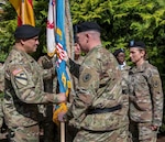 Army Brig. Gen. Eric P. Shirley, Defense Logistics Agency Troop Support commander passes the unit colors to the incoming commander, symbolizing that Army Lt. Col. Fermin Gonzales Jr. has taken command of DLA Troop Support Europe & Africa during a ceremony June 17 in Kaiserslautern, Germany.