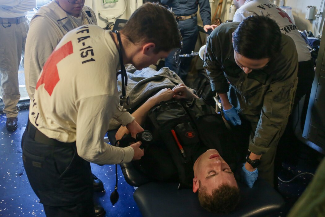 PHILIPPINE SEA (June 21, 2022) Sailors checks the vitals of Fireman Jarin Meyer, from Piqua, Ohio, in the flight deck battle dress station during a search and rescue drill onboard the Nimitz-class aircraft carrier USS Abraham Lincoln (CVN 72). Abraham Lincoln Strike Group is on a scheduled deployment in the U.S. 7th Fleet area of operations to enhance interoperability through alliances and partnerships while serving as a ready-response force in support of a free and open Indo-Pacific region. (U.S. Navy photo by Mass Communication Specialist Seaman Aleksandr Freutel)
