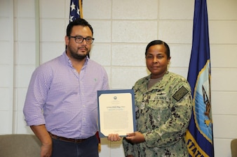 PENSACOLA, Fla. - Naval Education and Training Professional Development Center Commanding Officer, Capt. Willie Brisbane, presents Herm Pliego-Flores with a certificate for winning the senior civilian of the quarter (COQ) for first quarter, 2022. Pliego-Flores’ selection was based on his superior performance and selfless dedication to the Navy Advancement Center's (NAC) mission by serving as a key member of the NAC’s Equivalent Exam and Electronic Exam Administration team. Pliego-Flores was instrumental in the development of pilot exams for the Retail Specialist rating. (U.S. Navy photo by Cheryl Dengler)