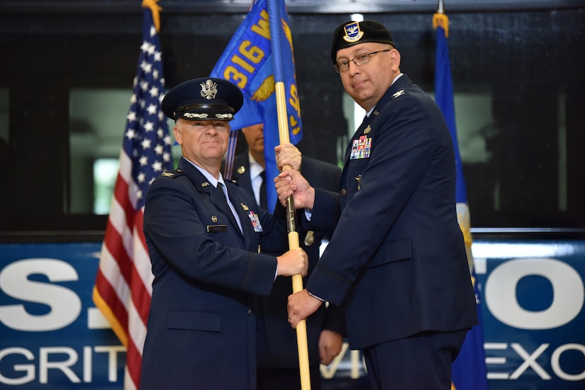 Two male air force colonels pass a military guidon during a change of command.